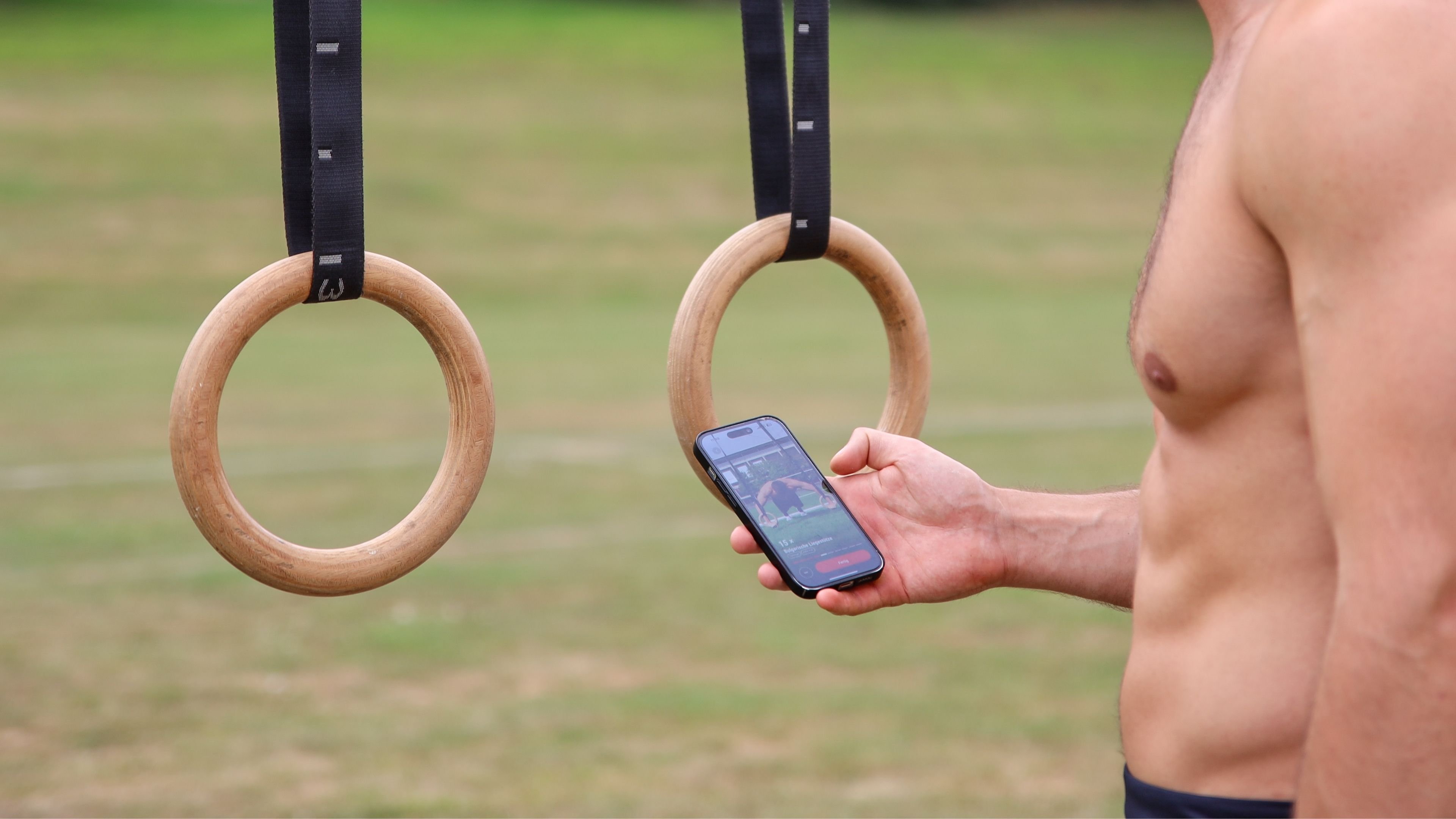 Turnringe neben einem Smartphone mit der DIE RINGE App